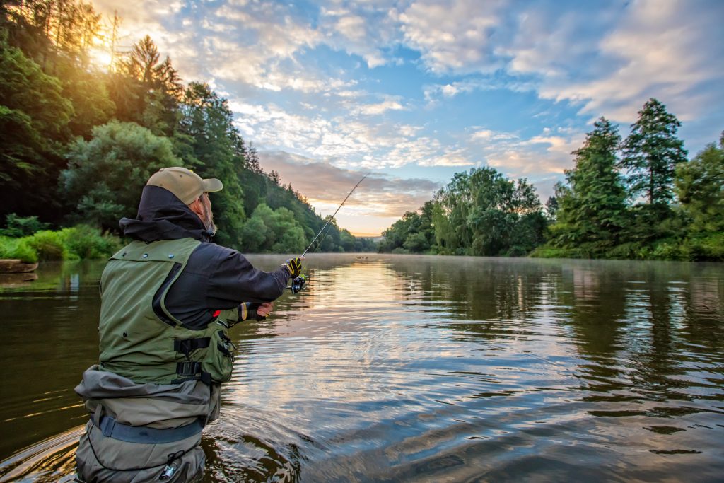 Sport fisherman. Outdoor fishing in river during sunrise. 