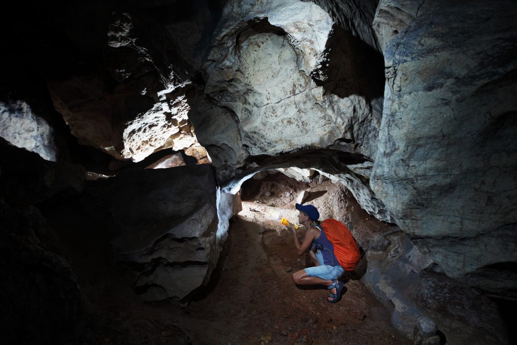 Woman exploring a cave with a flashlight