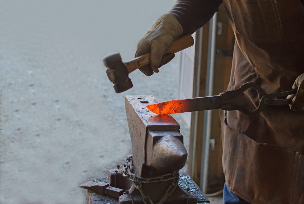 hot metal being forged into a knife on an anvil