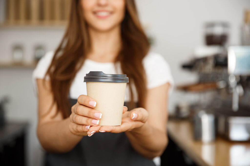 female barista serving a to go cup of coffee